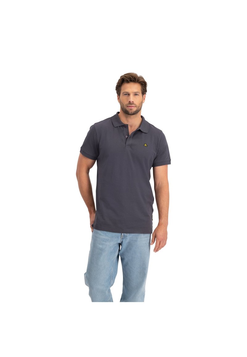 Donkergrijze polo met een kraag en korte mouwen, voorzien van een klein geel logo op de linkerborst, gecombineerd met lichtblauwe jeans.