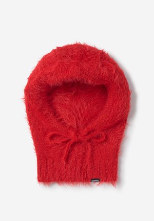Pasamontañas de punto peludo rojo con un pequeño lazo en el cuello y una etiqueta negra visible en el borde inferior.