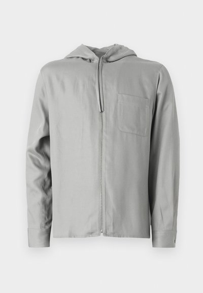 Ανοιχτό γκρι φούτερ με φερμουάρ και μακριά μανίκια, τσέπη μπροστά και επενδεδυμένη κουκούλα. Λείος υφή με απλό σχέδιο και χωρίς ορατά μοτίβα.