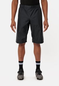 Pantaloni corti neri, leggeri, con una cintura elastica, taglio fino al ginocchio e una texture liscia, abbinati a calze nere con strisce bianche.