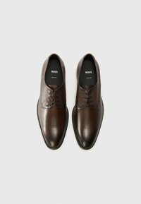 Zapatos de piel marrón con cordones y un acabado pulido, puntera redondeada y un sutil contraste de textura en la parte superior. Marca en las plantillas.