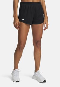 Pantalones cortos deportivos de malla negros con cintura elástica y bolsillos laterales. Combinándolos con zapatillas blancas con detalles en gris y negro.