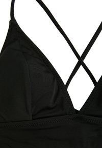 Zwarte driehoekige bikini-top met gladde stof, gekruiste rugbanden en subtiele stiksels langs de randen. Geen patronen of extra accenten.