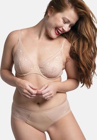 Soutien-gorge en dentelle nude avec des motifs géométriques et des bretelles réglables, associé à une culotte hipster transparente assortie avec des accents en dentelle.