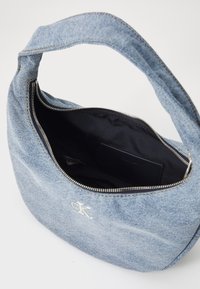 Jeans skulderveske med avrundet form og sølvglidelås. Innvendig er den svart, med en lomme og preget logodetalj.