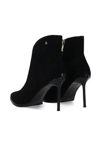 Černé semišové kotníkové Boty s elegantním designem, které mají vysoký stiletto podpatek a zlatý zip na zadní straně. Povrch je měkký a matný.