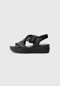 Sandales en cuir noir avec une plateforme tressée, présentant des brides croisées et une fermeture à boucle sur le côté. Texture lisse, design ouvert à l'avant.