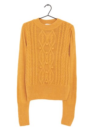 Pull en tricot jaune moutarde avec motifs torsadés et boules, manches longues, col rond, suspendu sur un cintre noir.