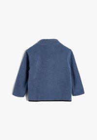 Blaue Fleecejacke mit Kragen, langen Ärmeln und geradem Schnitt. Sie hat eine strukturierte Oberfläche und einen kontrastierenden schwarzen Saum.