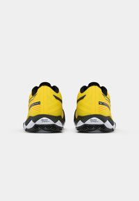 Des chaussures de sport jaunes avec un dessus texturé, des accents noirs et une semelle intermédiaire blanche. Elles présentent un motif de semelle unique sur la semelle extérieure.
