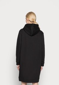 Svart huva sweatshirtklänning med långa ärmar, avslappnad passform och ribbade mudd. Mjuk textur, mitt på låren längd, minimalistisk design.