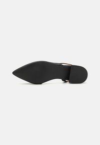 Zapato de tacón alto negro con punta afilada, parte superior de cuero suave, una correa delgada en el tobillo y suela de goma texturizada.
