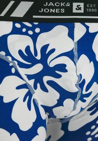 Men's boxer briefs with a black waistband featuring "Jack & Jones." Blue fabric with large white floral patterns. Soft, stretchy cotton material.