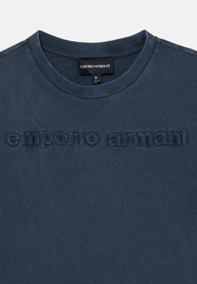 Navy plavi majica s okruglim izrezom s teksturiranim izvezenim logotipom "emporio armani" na prsima i crnom oznakom brenda unutar ovratnika.