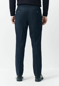 Dark blue tailored trousers made of textured fabric, featuring two back pockets with button closures and a straight-leg cut.