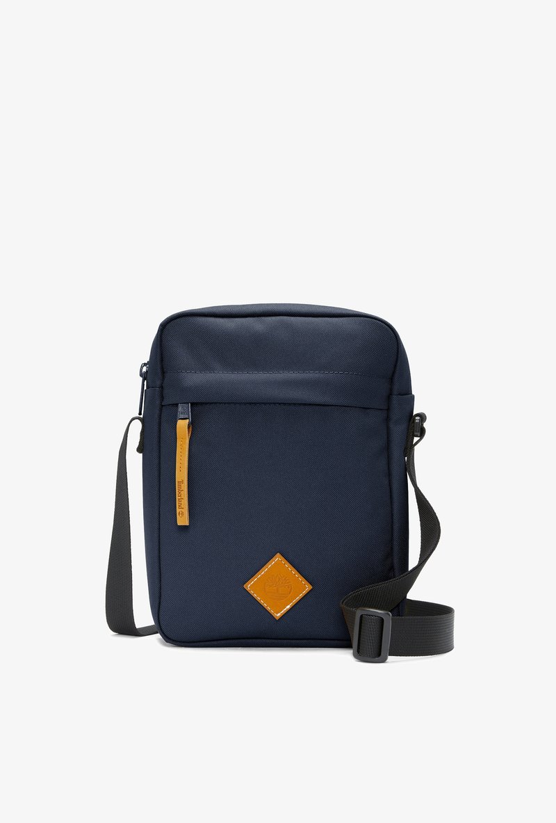 Borsa a spalla in tessuto blu navy con tracolla regolabile, chiusura con zip, patch in pelle sulla parte anteriore e texture liscia.