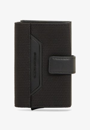 Cartera de tela texturizada negra con una correa de cuero y el nombre de la marca grabado en relieve en un pequeño parche de cuero, plegada y cerrada.