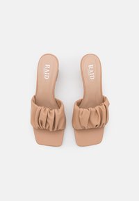 Sandalias de slip-on de ancho amplio en color beige con tira fruncida y punta cuadrada, etiquetadas "RAID" en la plantilla acolchada, dispuestas sobre un fondo blanco.
