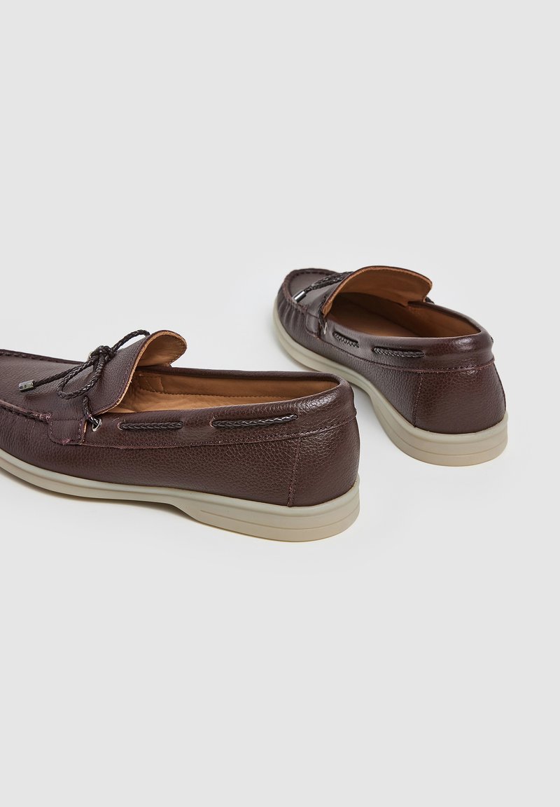 Mocassins en cuir marron foncé avec une surface texturée, des détails en lacet et des semelles en caoutchouc beige. Présentent un design de style mocassin avec une couture supérieure.
