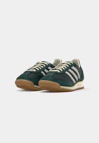 Green and grey retro sneakers with white stripes, suede material, textured upper, and gum rubber outsole, featuring a classic lace design.