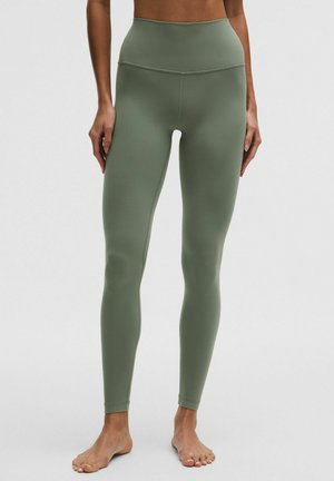 Legginsy o wysokim stanie w oliwkowym zielonym kolorze, wykonane z gładkiego, elastycznego materiału. Charakteryzują się dopasowanym krojem i bezszwową konstrukcją zapewniającą komfort i swobodę ruchów.