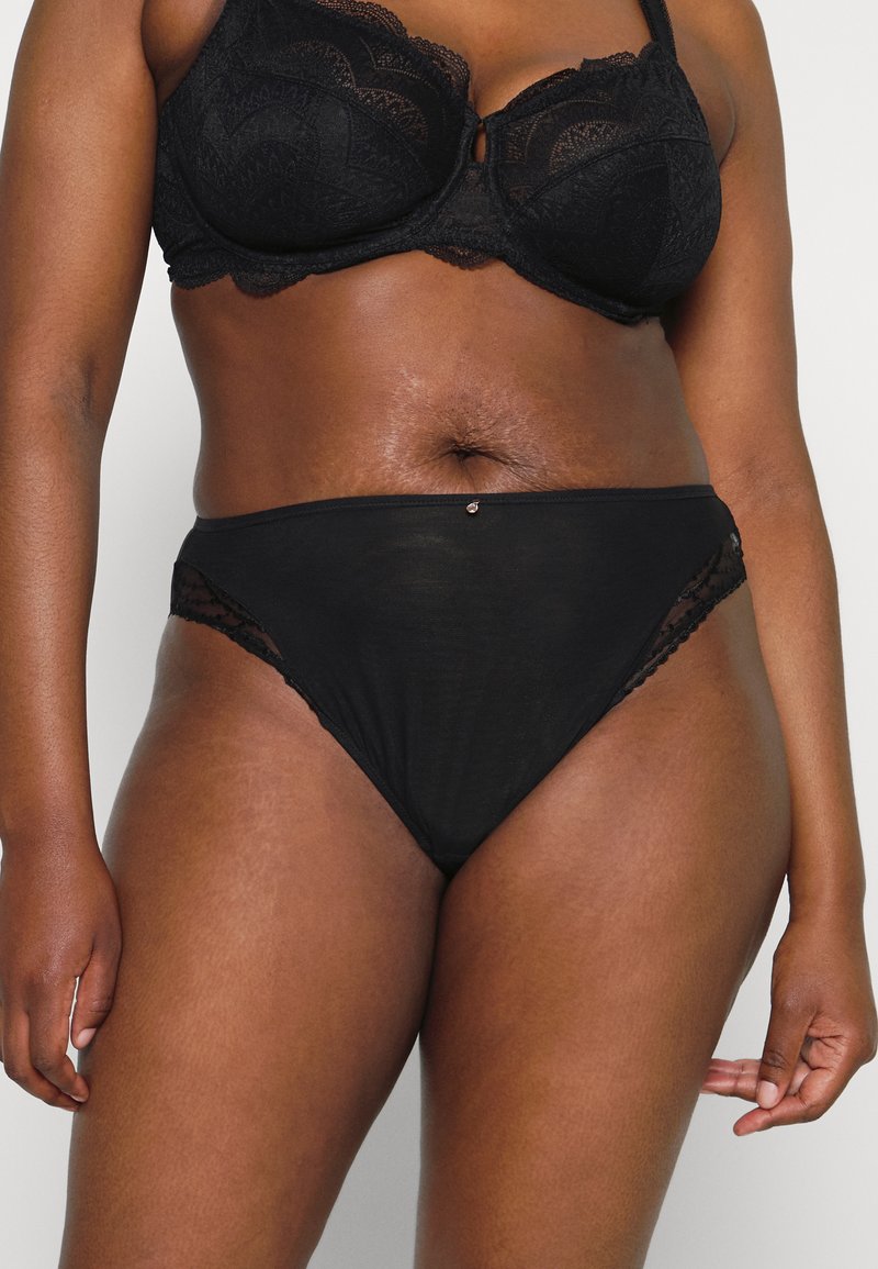 Panties de talle alto con borde de encaje negro que presentan un panel transparente suave a los lados y un pequeño acento decorativo en la cinturilla.