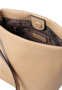 Beige leren totebag met een gestructureerd oppervlak. Heeft binnenin één vak met rits, voorzien van een bijpassende stoffen voering.