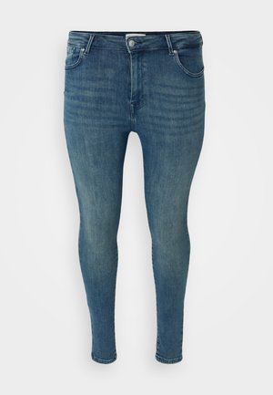 Jean skinny en denim bleu medium avec une texture lisse, design à cinq poches, passants de ceinture et fermeture à bouton à la taille.