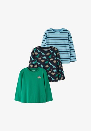 Trois chemises enfants à manches longues : une verte avec un petit dinosaure, une marine avec un motif dinosaure multicolore, une bleu clair avec rayures noires.