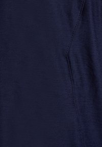 Gros plan sur un tissu bleu foncé montrant une couture détaillée le long d'une couture avec une surface légèrement texturée et lisse.