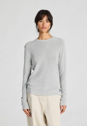 Light gray long-sleeve sweater with a ribbed texture, round neckline, and extended cuffs, paired with beige relaxed-fit pants.