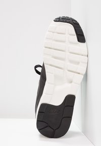 Musta lenkkari, jossa on teksturoitu kumipohja. Varustettu valkoisella välipohjalla ja erottuvalla Nike Air -logolla. Muotoilu sisältää virtaviivaisen muodon ja kengännauhat.