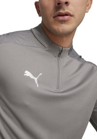 Grauer sportlicher Quarter-Zip-Pullover mit strukturiertem Design. Verfügt über ein kleines weißes Puma-Logo auf der Brust und einen Reißverschluss am Hals.