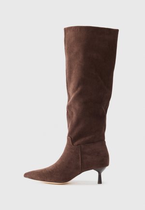 Cizmă maro din suede, până la genunchi, cu vârf ascuțit, tocul subțire și textură netedă; prezintă un design ajustat și o croială minimală.