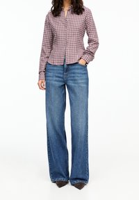 Koszula w kratę w kolorze burgundowym i białym; szerokie niebieskie jeansy; ciemne buty czółenka; luźny krój; długie rękawy.