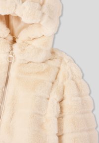 Kremowa kurtka z sztucznego futra z kapturem, z poziomymi, pikowanymi paskami i centralnym zamkiem błyskawicznym. Miękka tekstura z puszystym wykończeniem.