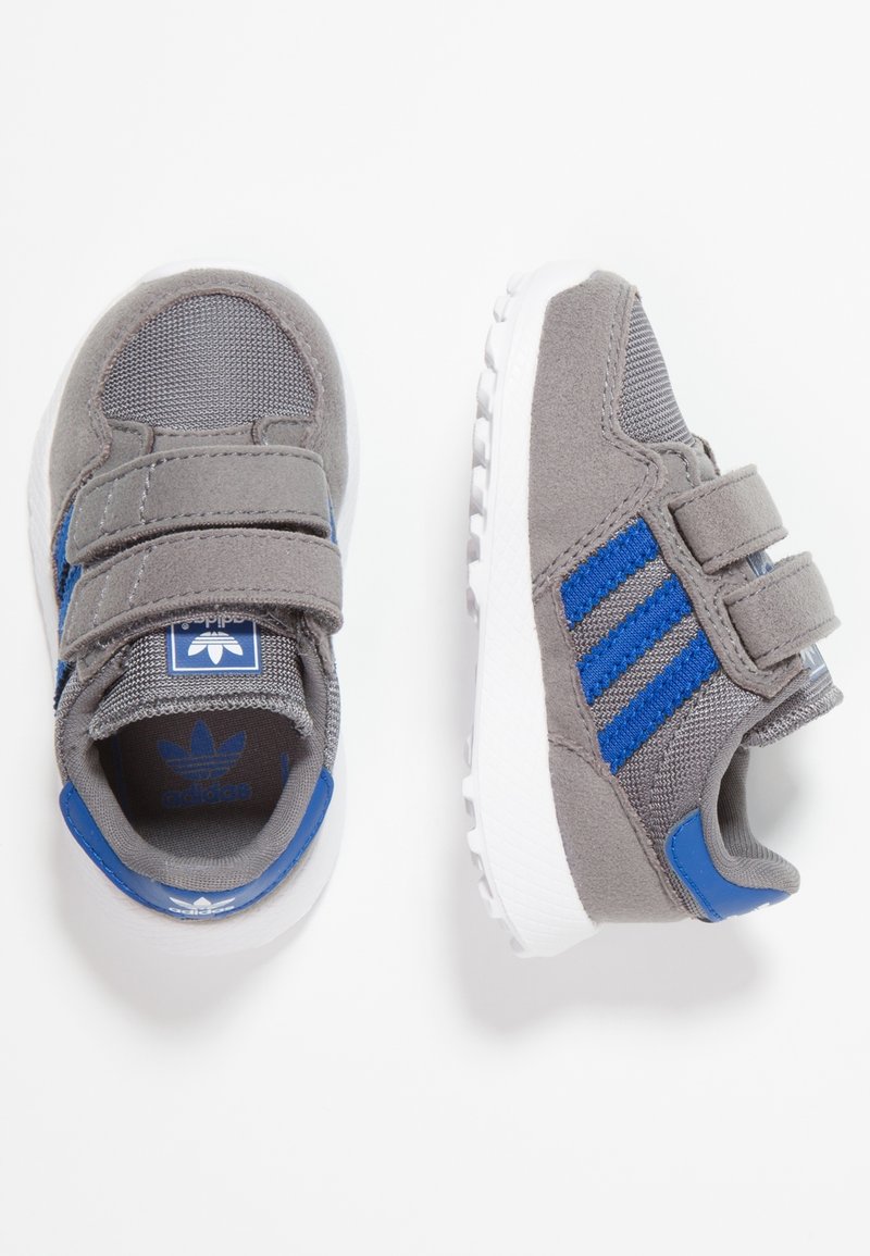 Harmaat urheilukengät, joissa siniset korostukset, valmistettu kankaasta ja synteettisistä materiaaleista. Varustettu tarranauhakiinnityksillä ja kuvioidulla kumipohjalla.