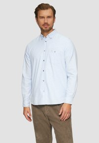 Lichtblauw geruit overhemd met lange mouwen, met een button-down kraag, een voorzak en stoffen knopen, gecombineerd met bruine corduroy broek.