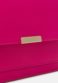 Borsa in finta pelle fucsia con texture liscia, caratterizzata da un elegante dettaglio rettangolare dorato e bordi cuciti con cura.