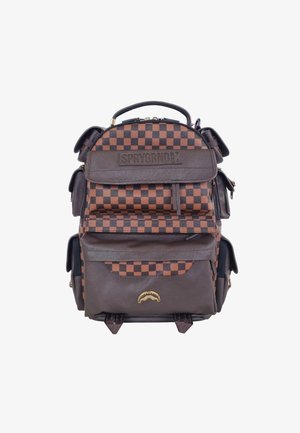 Zaino quadrato marrone e arancione con più tasche, spallacci regolabili, manico superiore e un emblema dorato sul davanti. Materiale resistente.