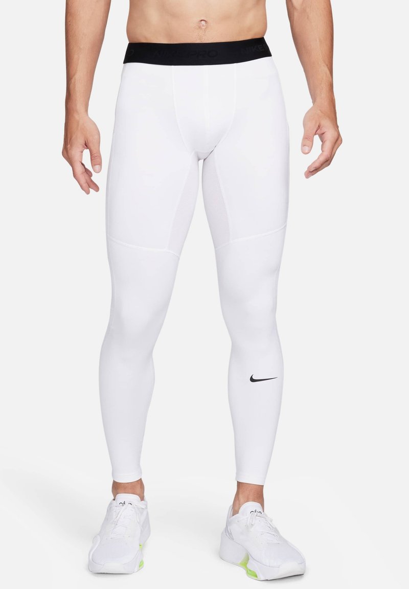 Leggings sportivi bianchi realizzati in materiale elastico, con vita nera Nike Pro e un piccolo logo Nike nero sulla parte inferiore della gamba.
