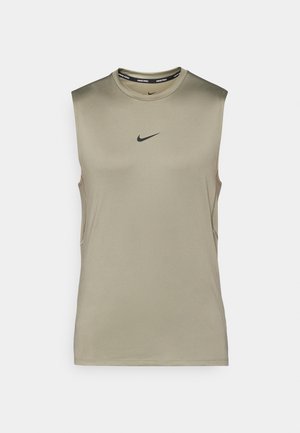 Sleeveless athletic top in light olive green, made of smooth fabric. Features a black Nike logo on the chest and subtle side slits.