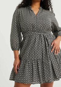 Vestido de estampado en blanco y negro con cuello de solapa, mangas tres cuartos y una falda acampanada fruncida en la cintura.