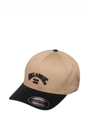 Beżowa i czarna czapka baseballowa Billabong z zakrzywionym daszkiem i naklejką Flexfit na froncie.