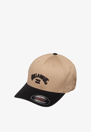 Beżowa i czarna czapka baseballowa Billabong z zakrzywionym daszkiem i naklejką Flexfit na froncie.