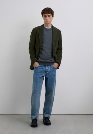 Blazer color verde oliva, suéter gris de cuello redondo, jeans relajados azul claro y zapatos negros. Tela suave y diseño estructurado.