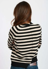 Maglione a righe nero e crema con maniche lunghe, scollatura rotonda e orlo a coste. Presenta un dettaglio di cucitura sul retro e una morbida texture a maglia.