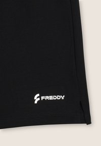 Pantalones cortos de algodón negros con corte recto, que presentan un logo blanco de "FREDDY" en la parte inferior izquierda. Aberturas sutiles en los laterales del dobladillo para mayor comodidad.