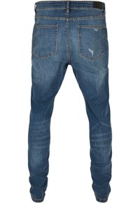 Modre denim hlače s ozkim krojem, z srednje visokim pasom, petimi žepi in rahlim zbledelostjo na stegnih ter zadnjih žepih.