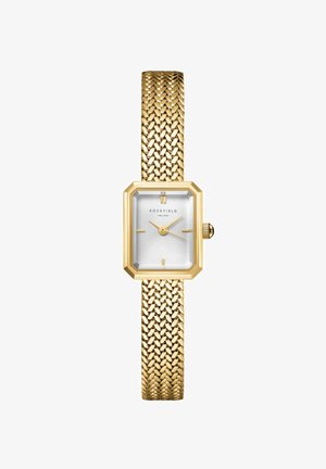 Reloj tono dorado con una esfera blanca octagonal y correa de malla texturizada. Presenta dos marcadores de hora dorados y una caja texturizada para mayor detalle.